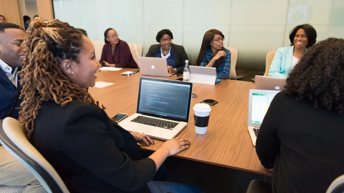 A team around a meeting table with laptops, in discussion