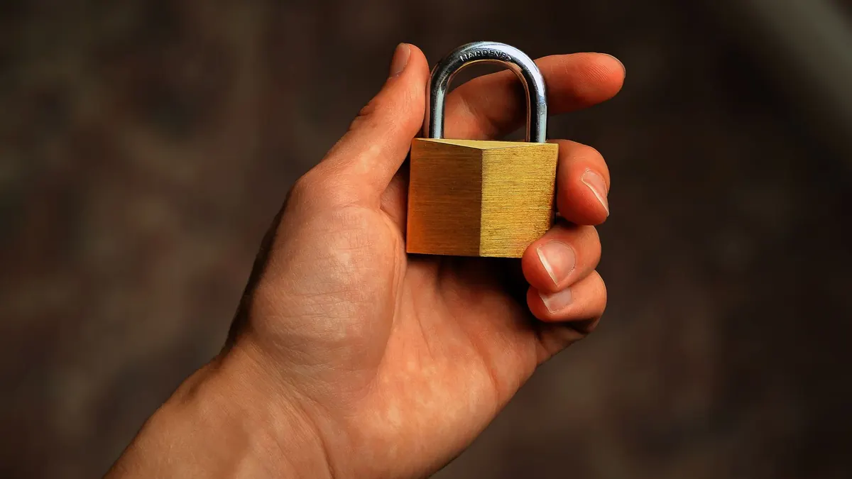 A hand holding a brass padlock
