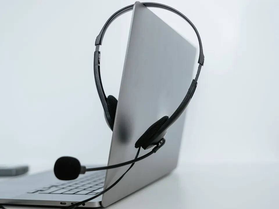 A laptop with a headset resting on it, ready for a support call