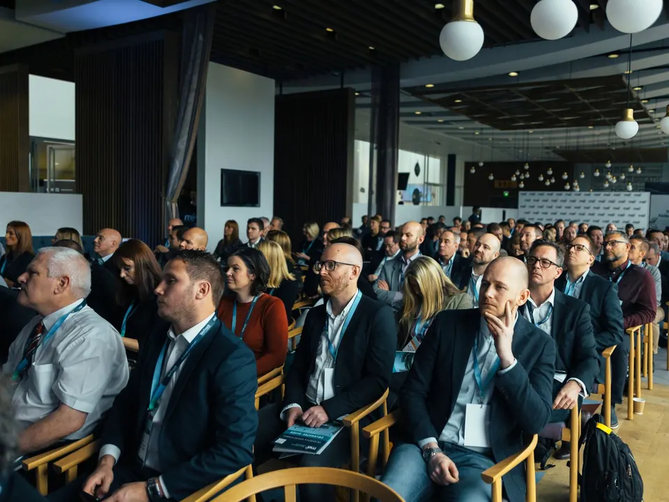 A large audience of professionals seated at a conference session